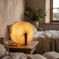 Folding book lamp glowing on a wooden nightstand