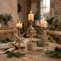 Gold Christmas candle holders with lit candles on a rustic wooden table
