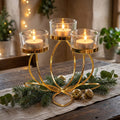 Gold lotus tealight holder with three lit candles on a rustic dining table