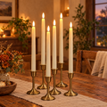 six ivory flameless LED taper candles in brass candlesticks on a rustic dining table