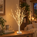 lighted birch tree with warm white LEDs glowing on a wooden table