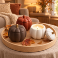 Ceramic pumpkin candle jars in rust red, white and chocolate on a wood tray