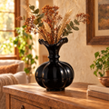 Black ceramic pumpkin vase with dried autumn stems