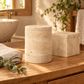 Travertine round canister and square box on a wooden bathroom vanity