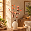 Faux persimmon branch in a cream ceramic vase