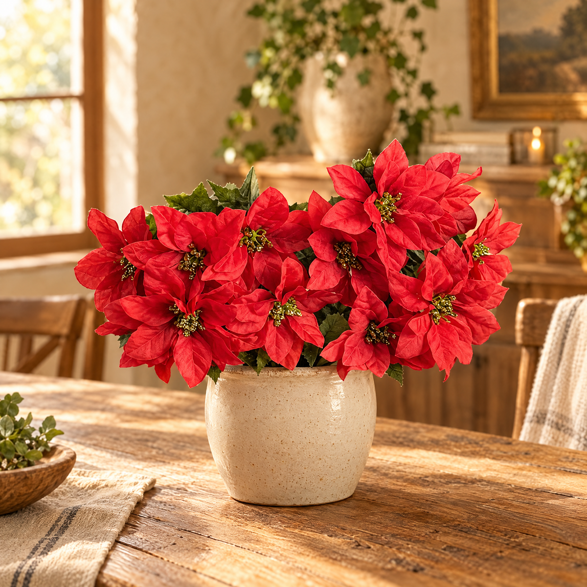 Red faux poinsettia bush in a cream pot on a rustic dining table