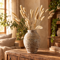 Rustic clay pottery vase with dried wheat on a wooden sideboard