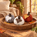 Three knit pumpkins in gray, white and orange on a wooden tray