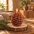 Brown pinecone candle lit on a wood slice with pine sprigs