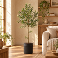 Faux olive tree in a black pot in a sunny living room corner