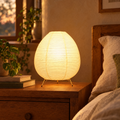 Glowing rice paper lantern lamp on a wooden nightstand