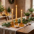 Three amber ribbed glass candle holders with lit taper candles on a rustic table