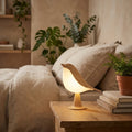 Wooden bird touch lamp glowing on an oak nightstand